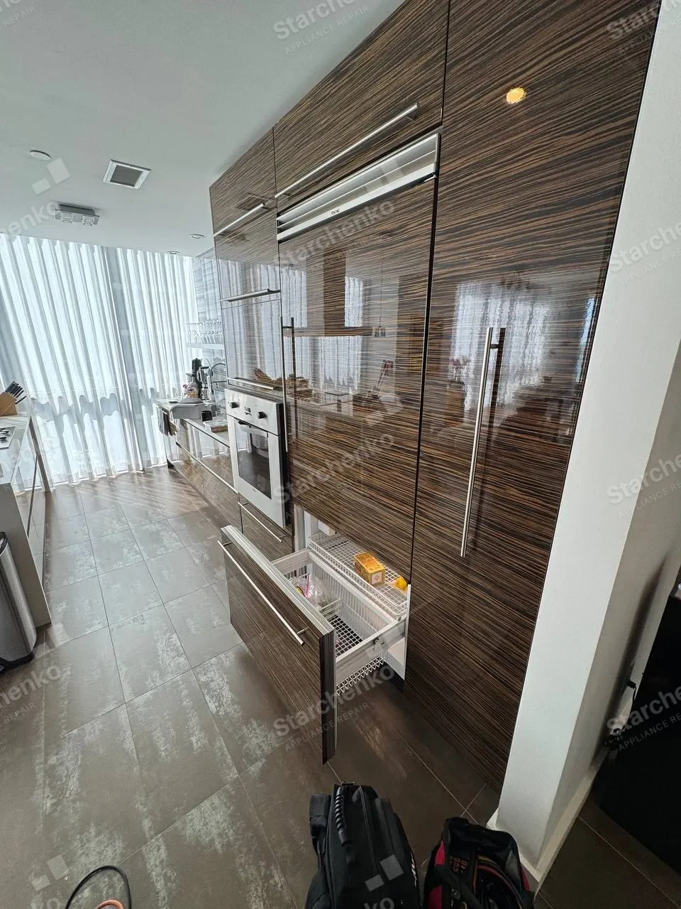 Thermador built-in freezer drawer pulled out of a dark wood kitchen column with the baskets visible
