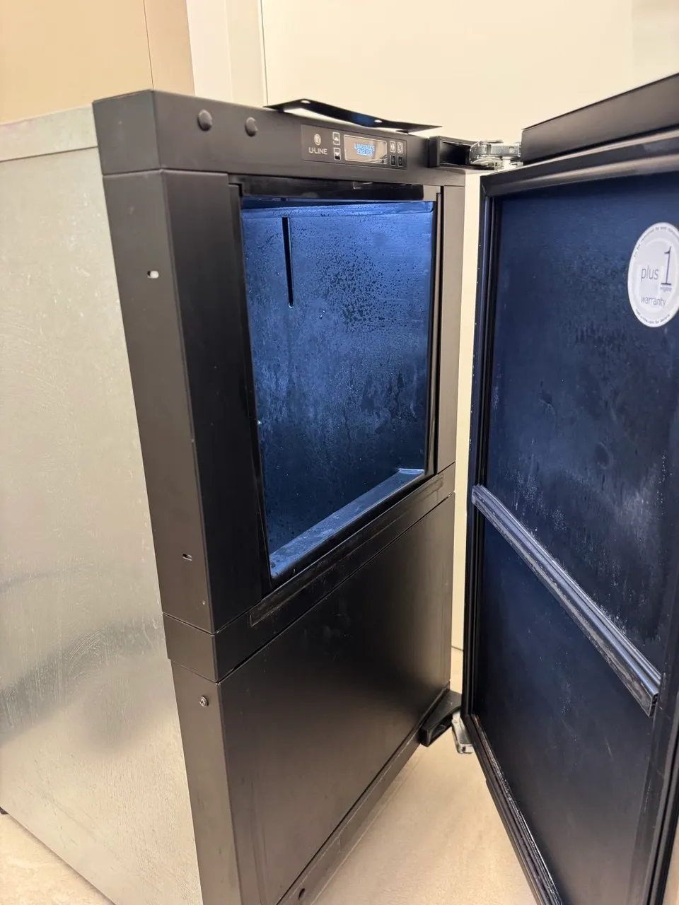 U-Line commercial ice machine with its door open and frost inside the empty bin