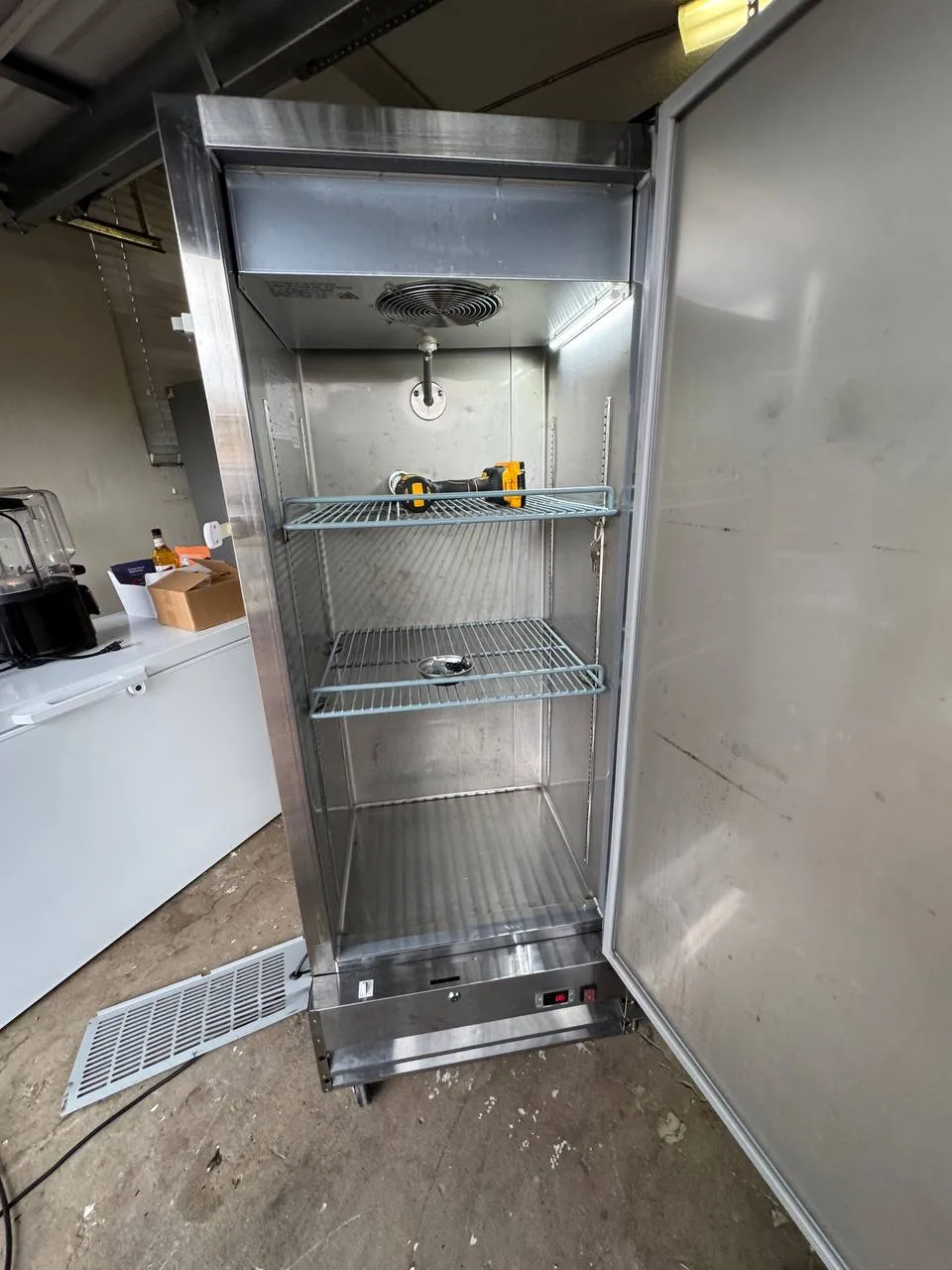 Stainless commercial reach-in cooler with the door open and evaporator fan visible