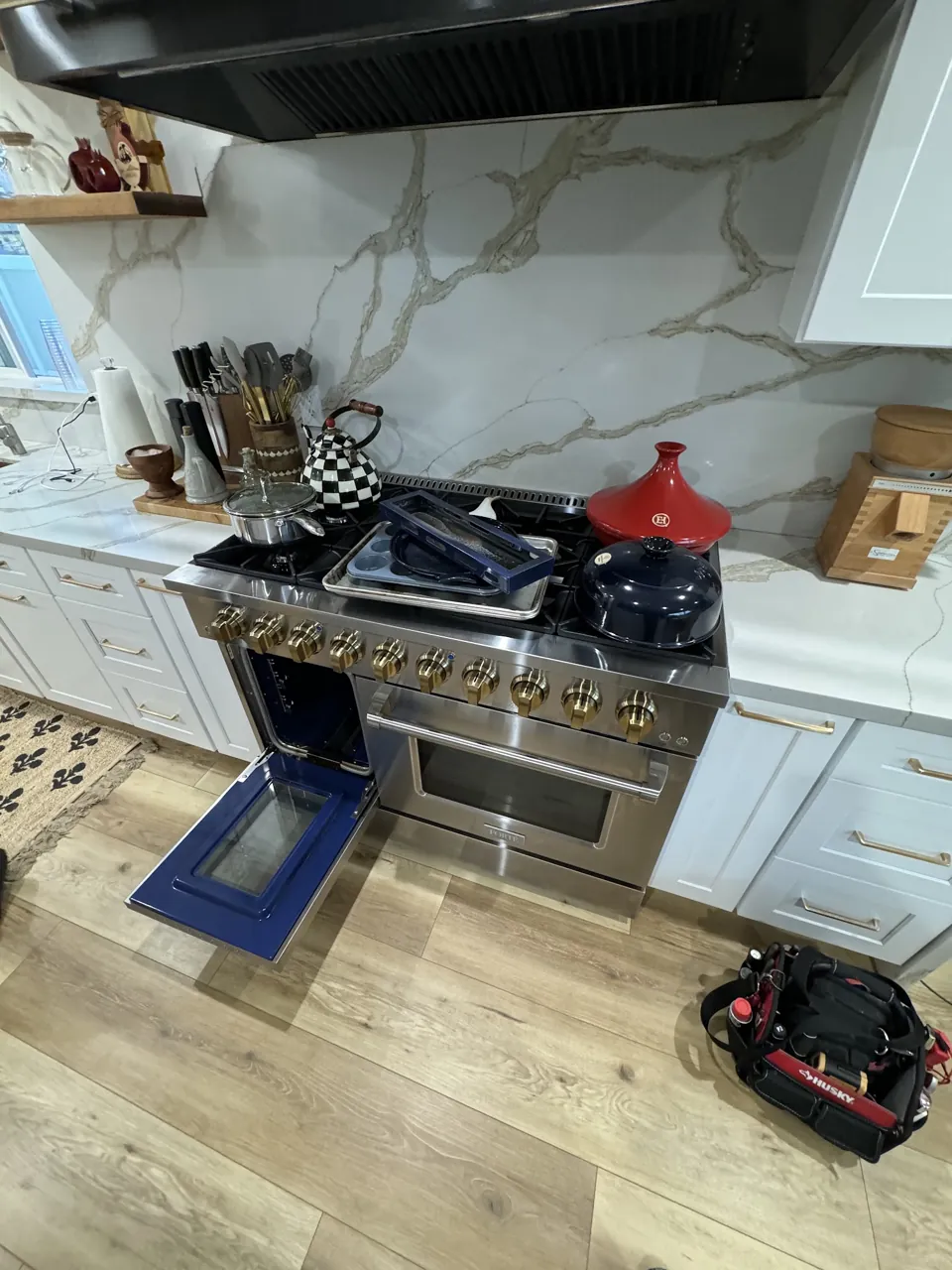 Pro-style gas range with one oven door open and the second door removed