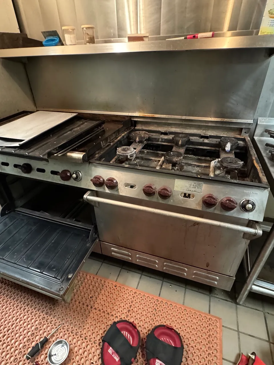 Commercial gas range and oven with burner grates removed and the oven door open