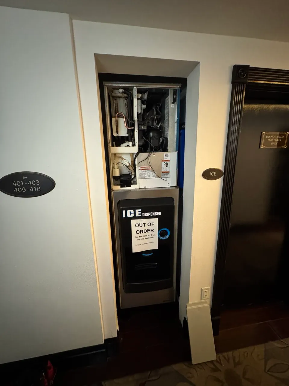 Hotel corridor ice machine dispenser with its top panel removed, exposing the compressor and lines