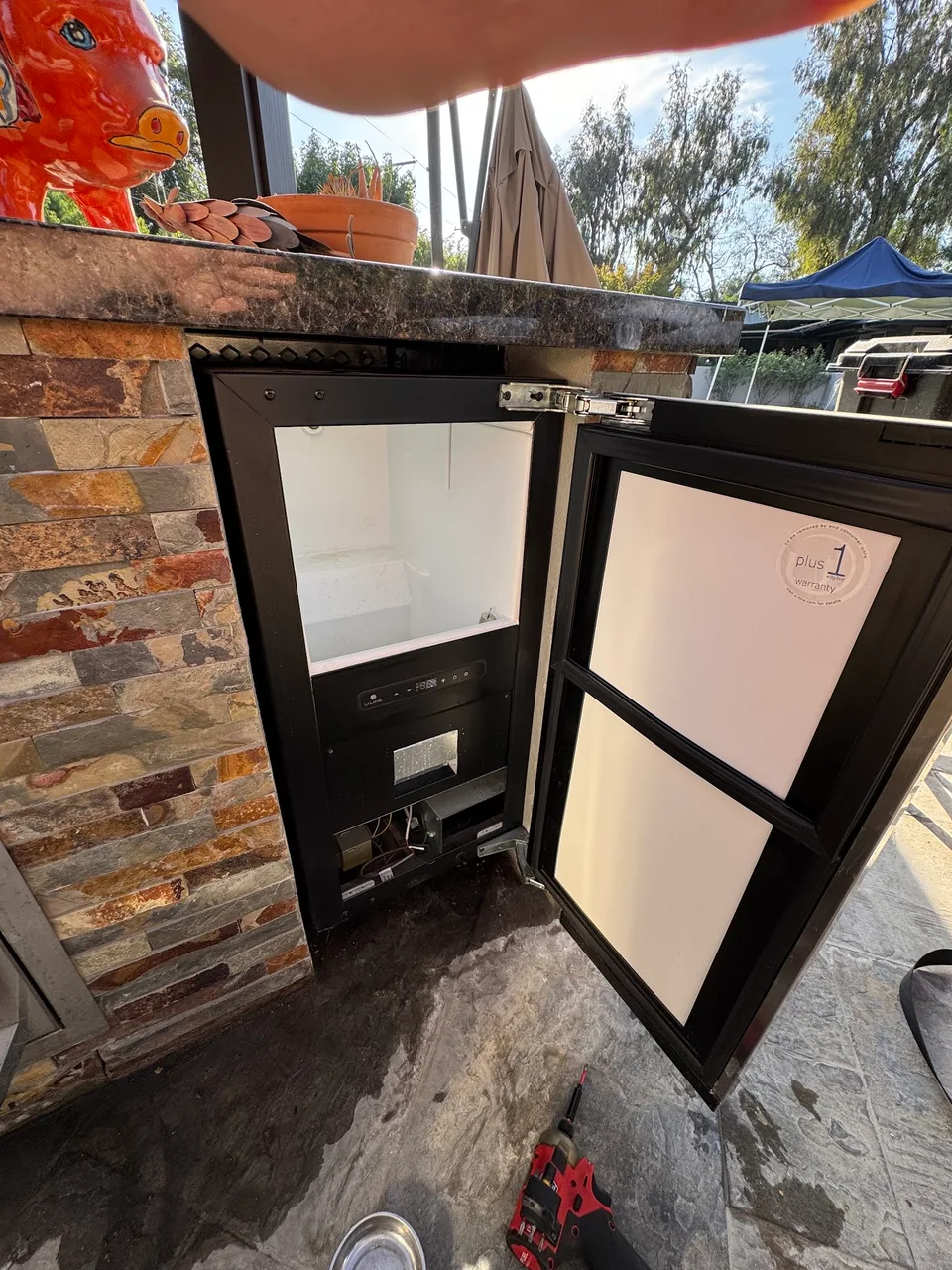Outdoor ice maker open with the empty bin and lower refrigeration components exposed