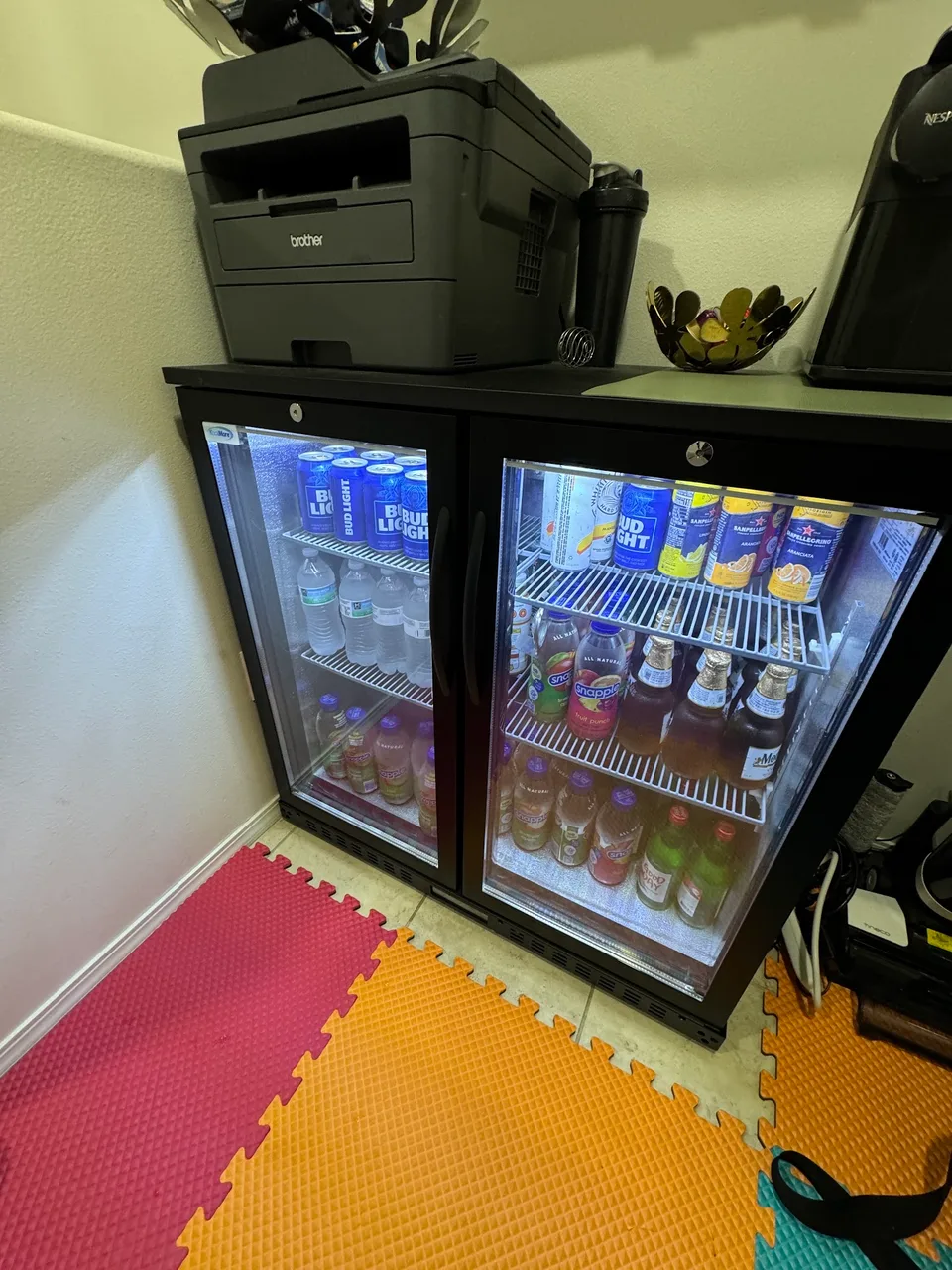 Glass-door wine cooler filled with beverages and condensation inside both doors