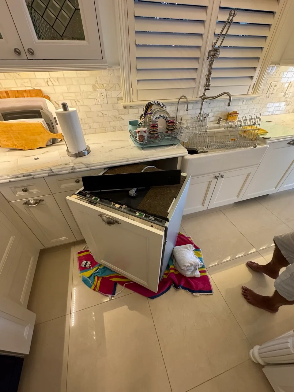 Panel-ready dishwasher pulled from white cabinetry with its top controls open