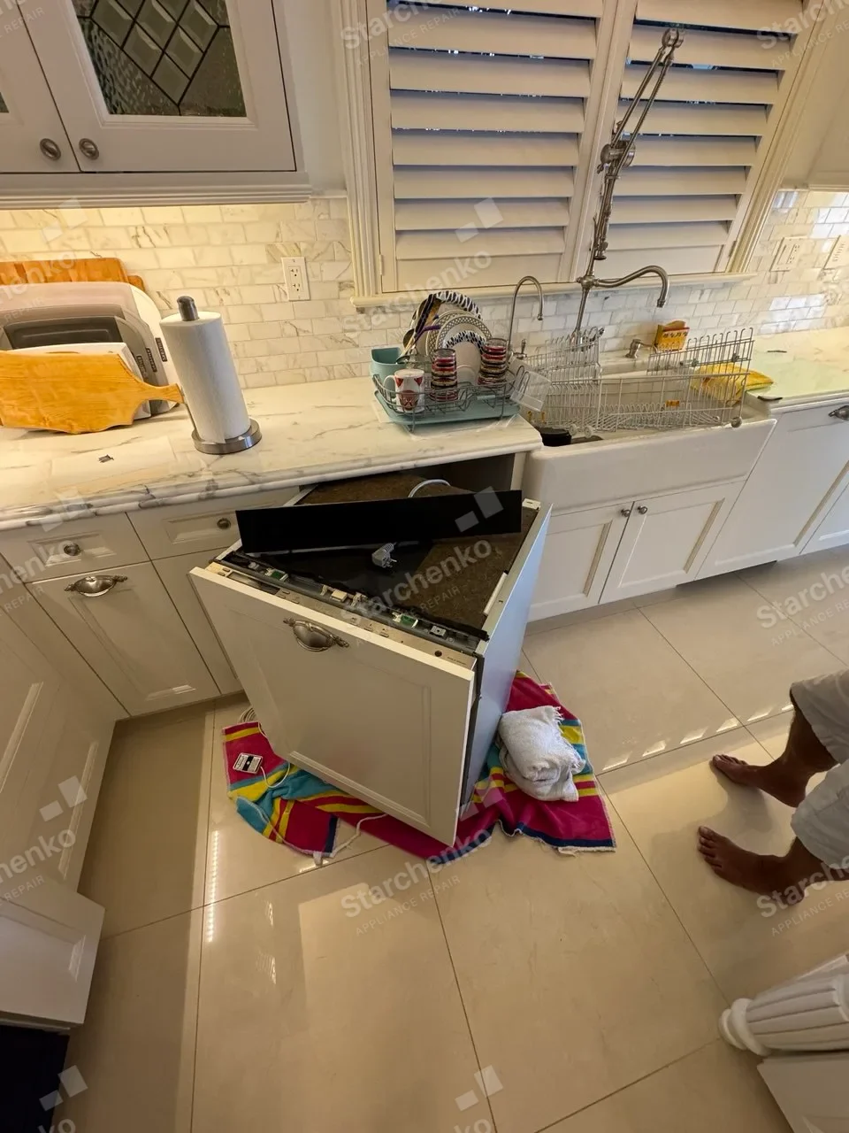 Panel-ready Thermador dishwasher pulled from white cabinetry with its top controls open