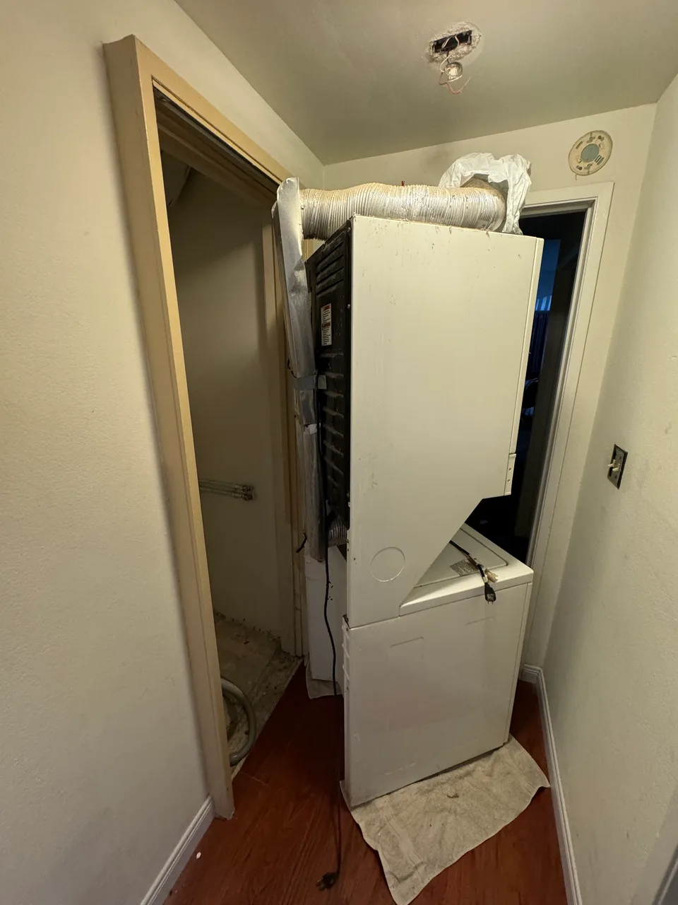 Stacked washer and dryer pulled from a closet with the rear service area and vent exposed