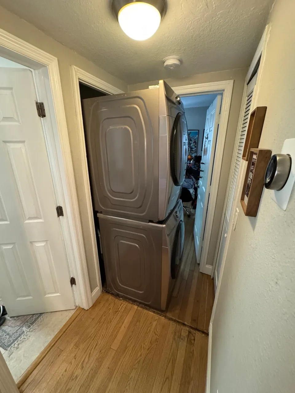 Stacked dryer in a hallway closet with the door open