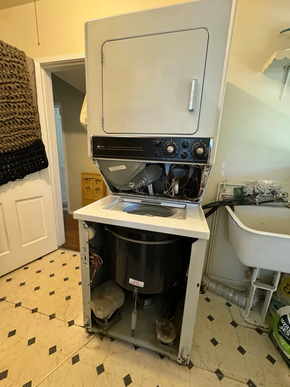 Stacked washer and dryer with both front service panels removed and the washer tub exposed