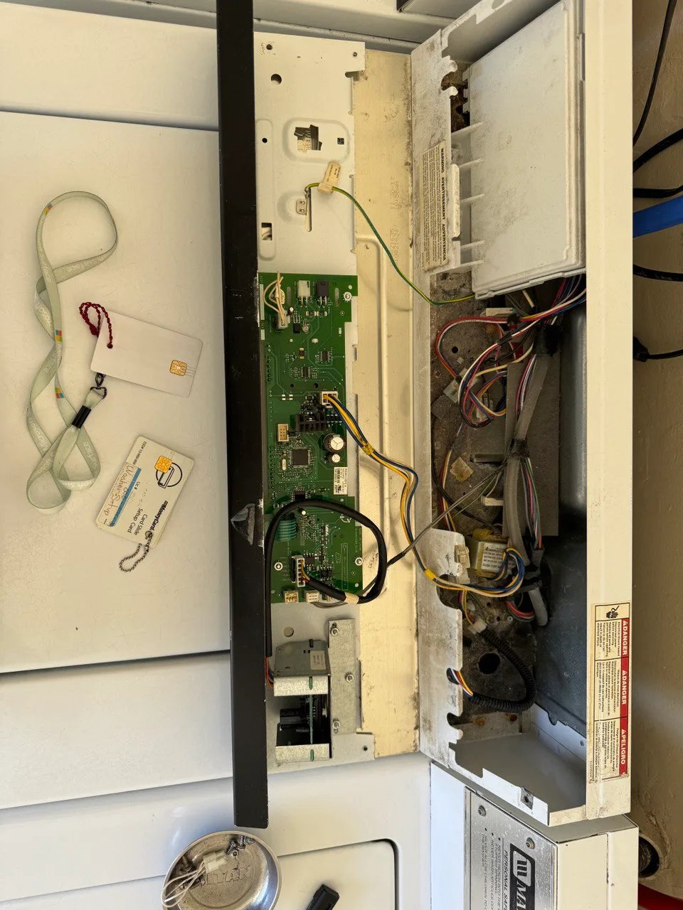 Commercial washer control panel opened to expose circuit boards, wiring and card keys