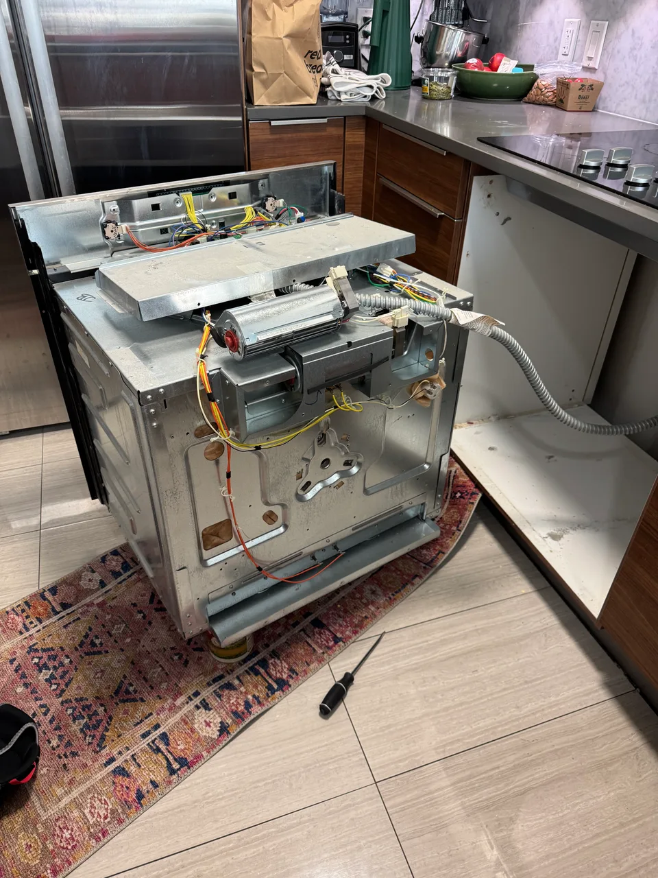 Bosch oven pulled from its cabinet with the cooling fan, wiring and controls exposed