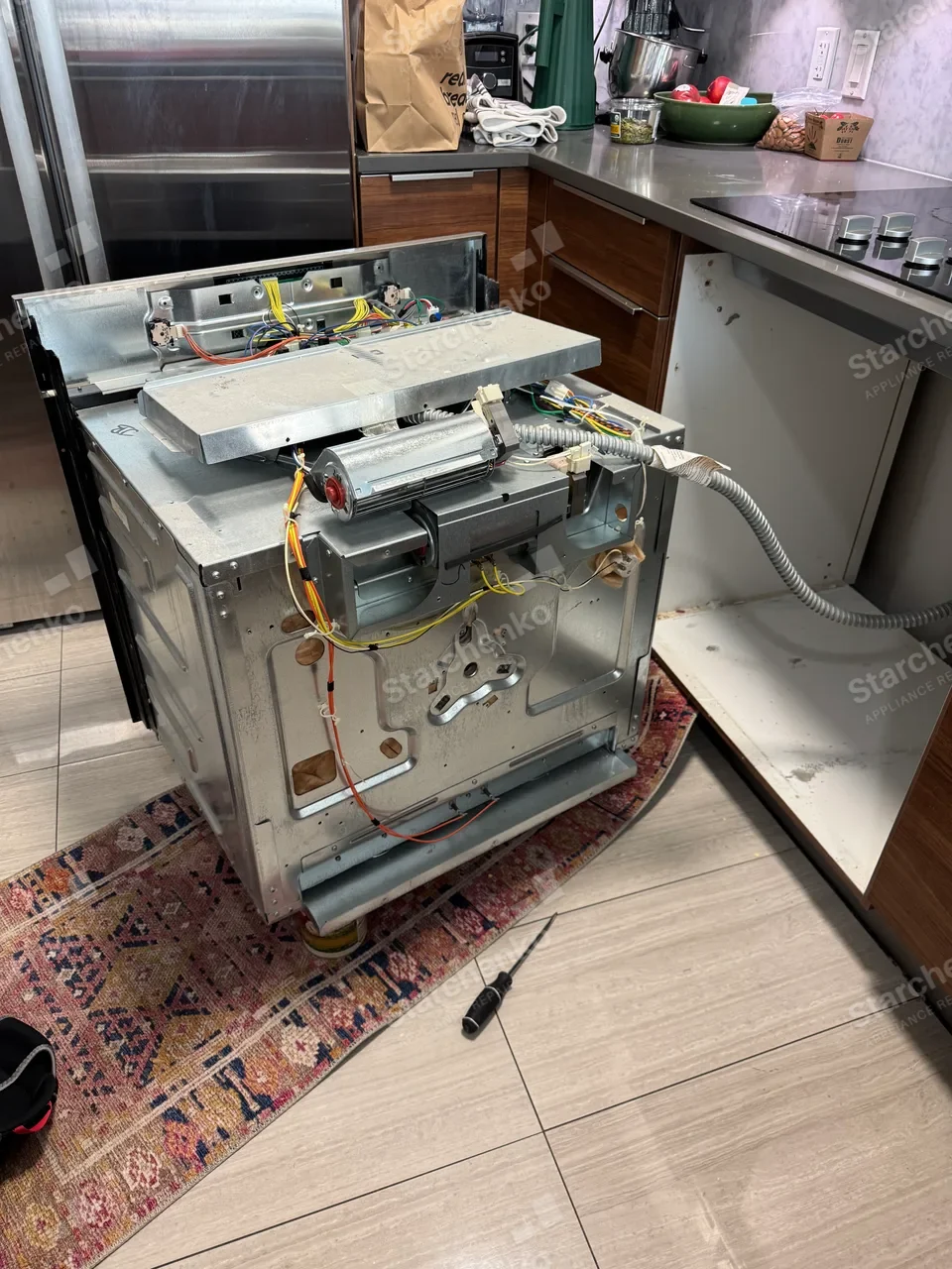 Bosch oven pulled from its cabinet with the cooling fan, wiring and controls exposed
