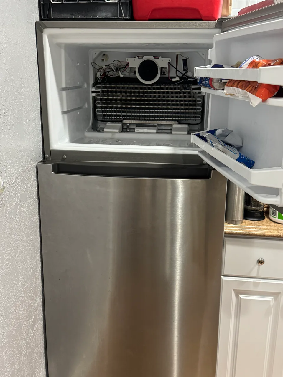 Refrigerator with the rear freezer panel removed to reach the evaporator and the drain