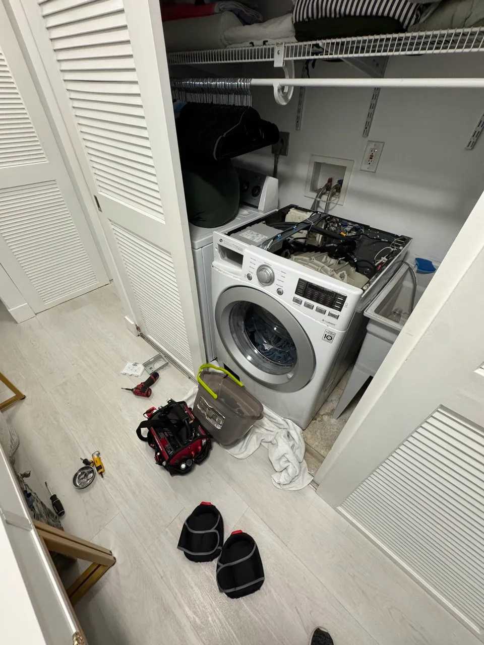 LG front-load washer in a closet with the top panel removed