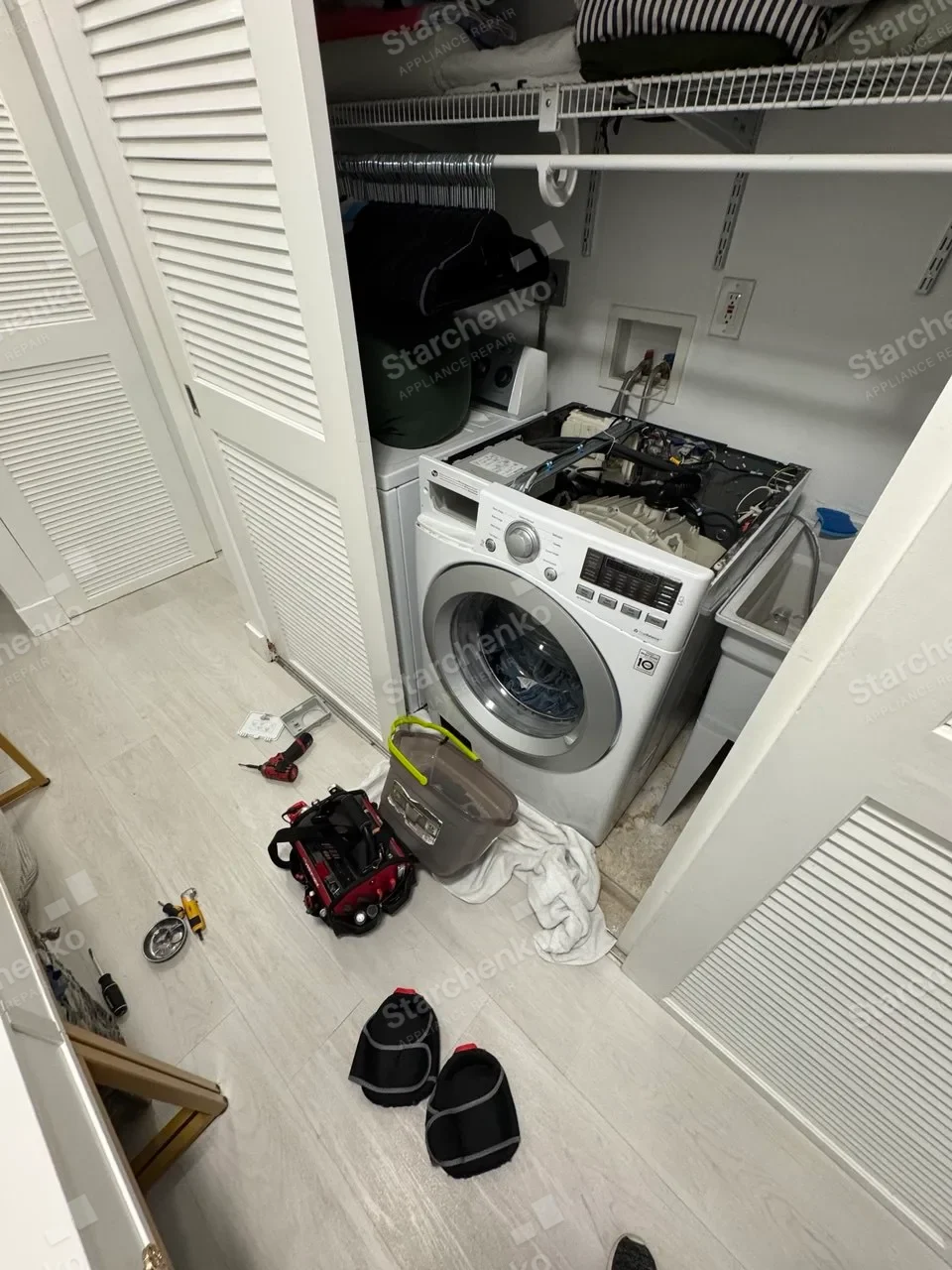 LG front-load washer in a closet with the top panel removed
