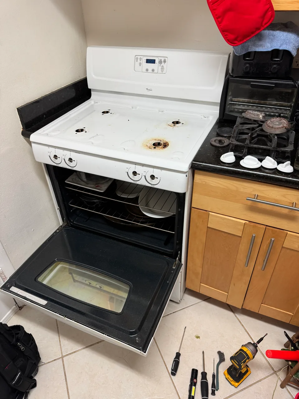 White gas range with burner grates and caps removed and the oven door open