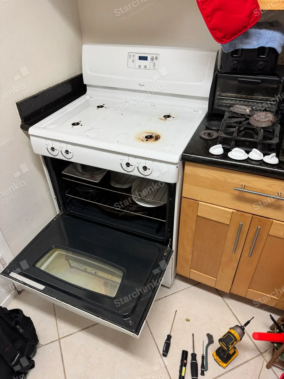 White Whirlpool gas range with burner grates and caps removed and the oven door open