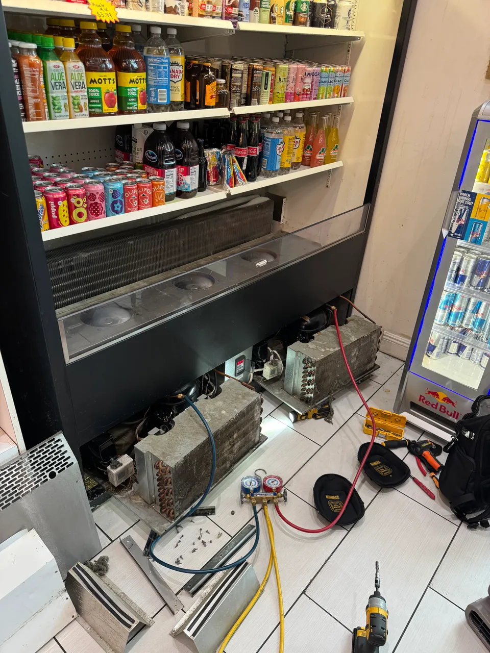 Commercial store cooler with two condensing units pulled out and refrigerant gauges connected