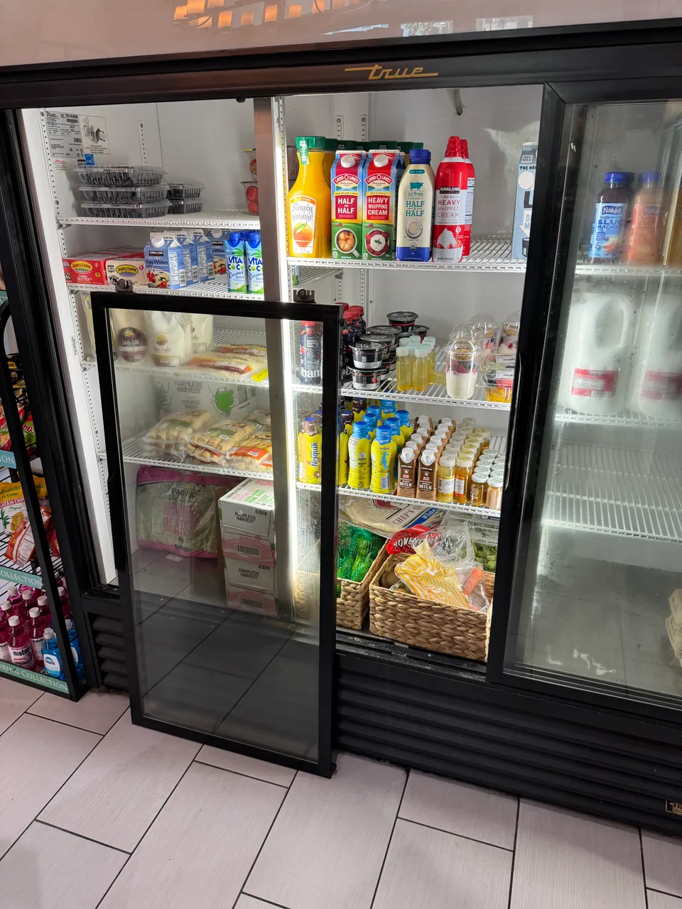 Commercial glass-door cooler with one sliding door taken out and standing beside it