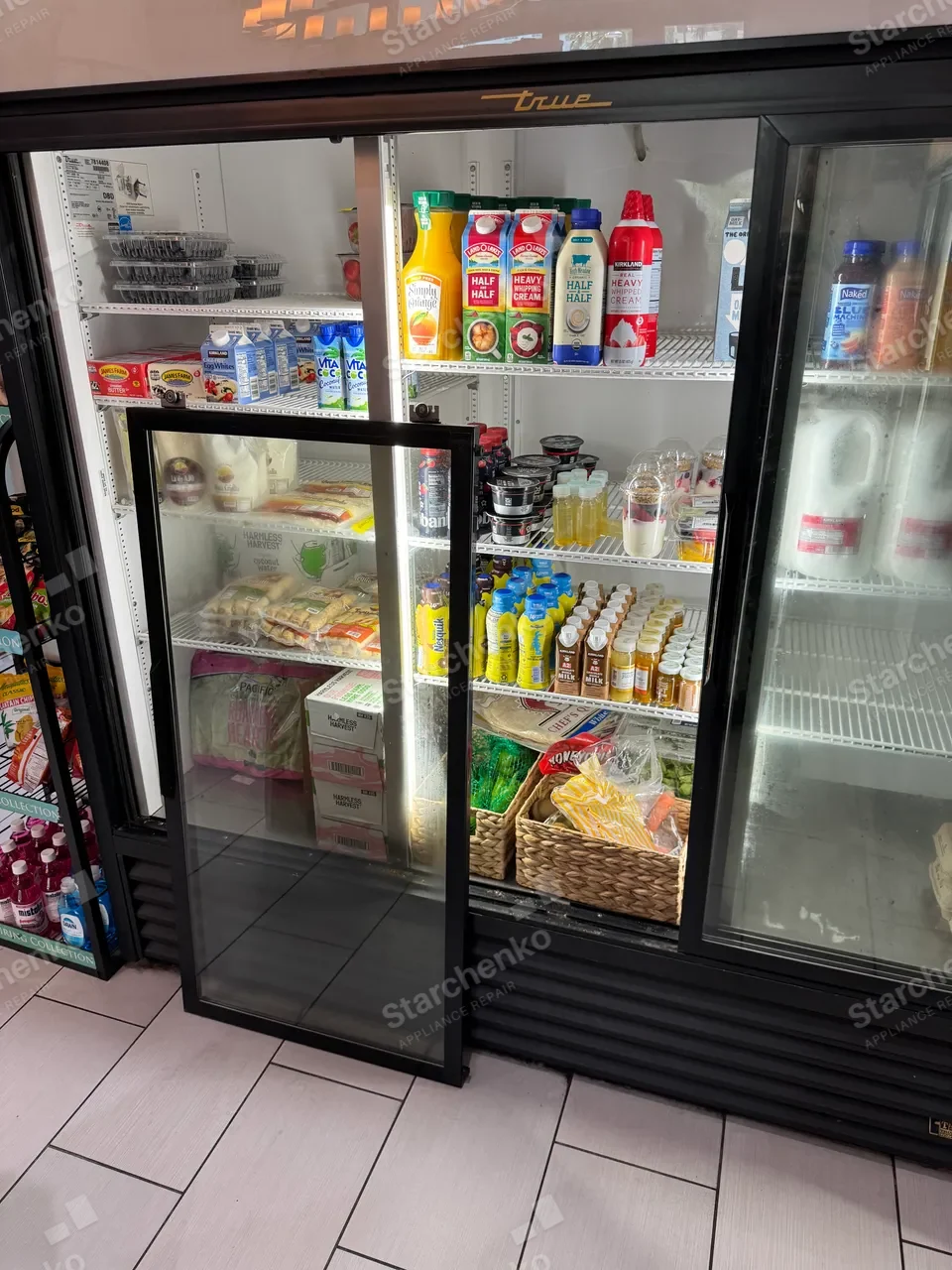 True commercial glass-door cooler with one sliding door taken out and standing beside it