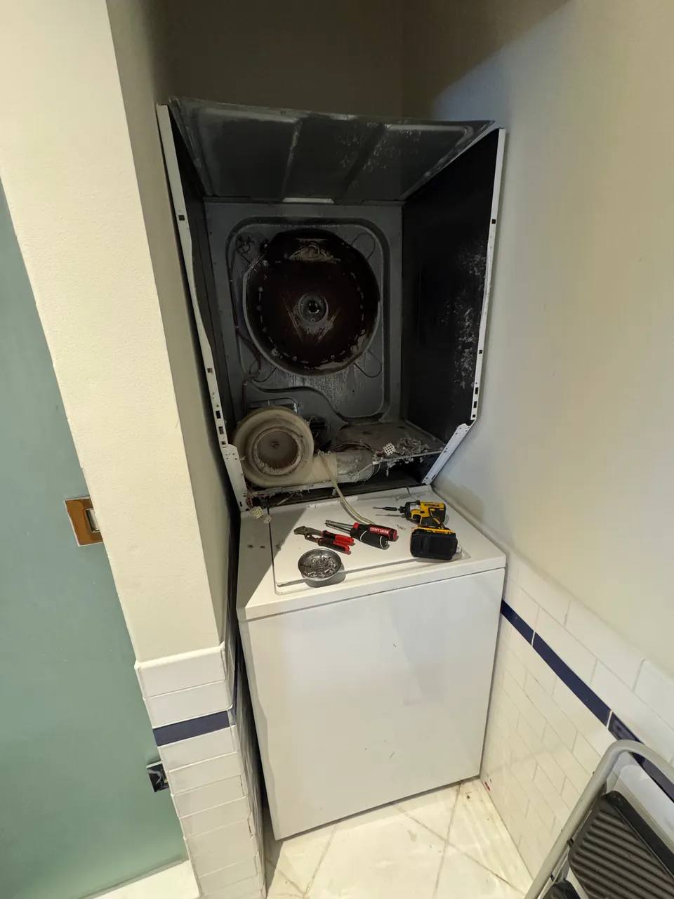 Laundry center with the dryer front removed, drum, blower wheel and lint area exposed