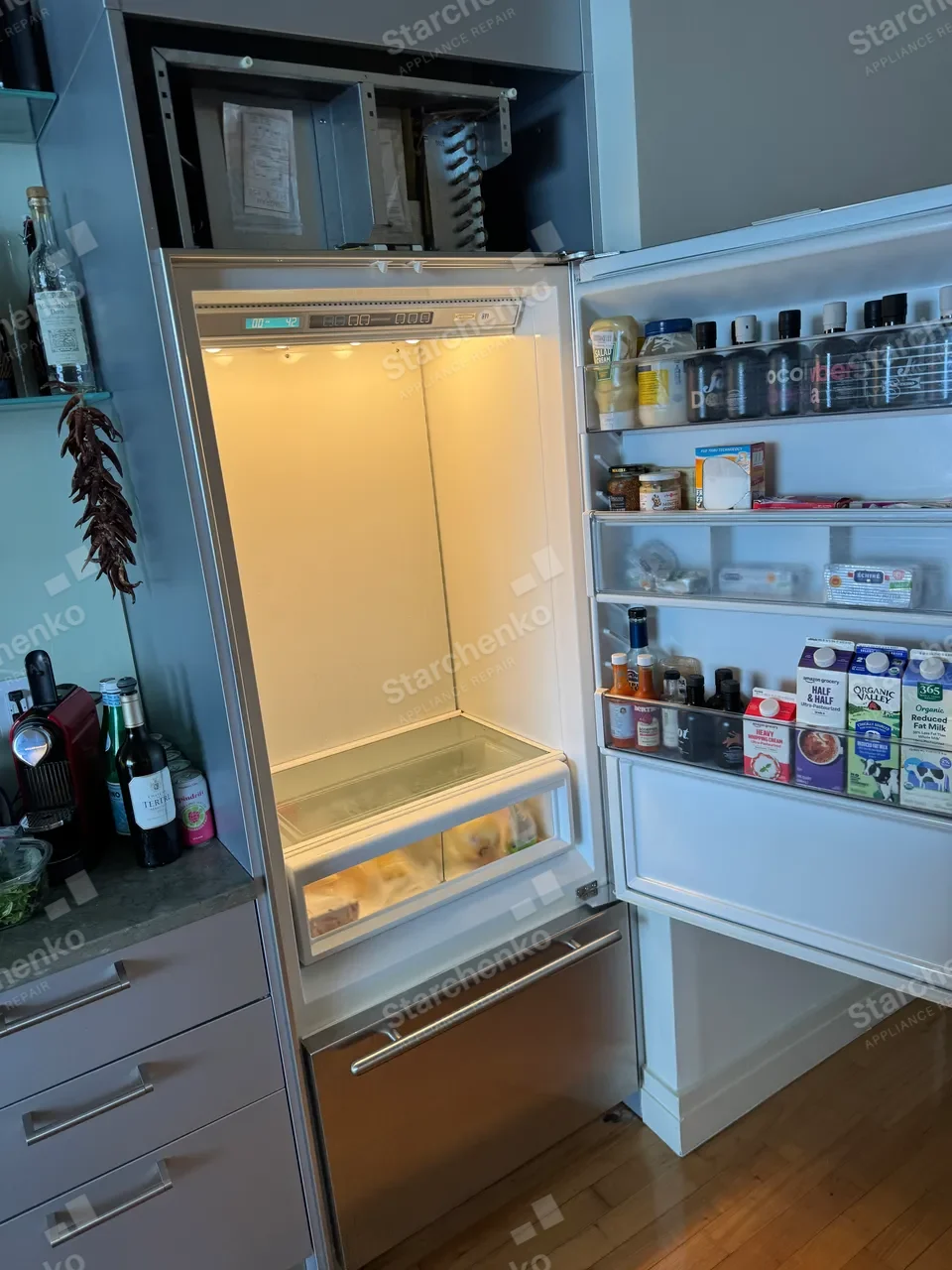 Sub-Zero built-in refrigerator with the top compressor compartment open and the fresh-food section empty