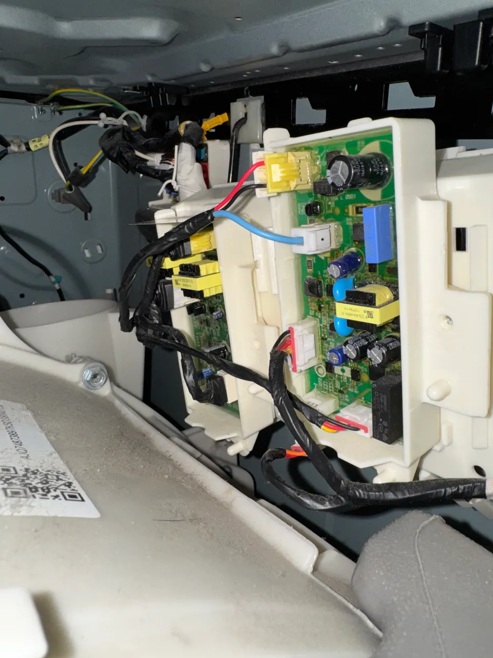Washer control panel opened up with the main control board and its wiring harness exposed