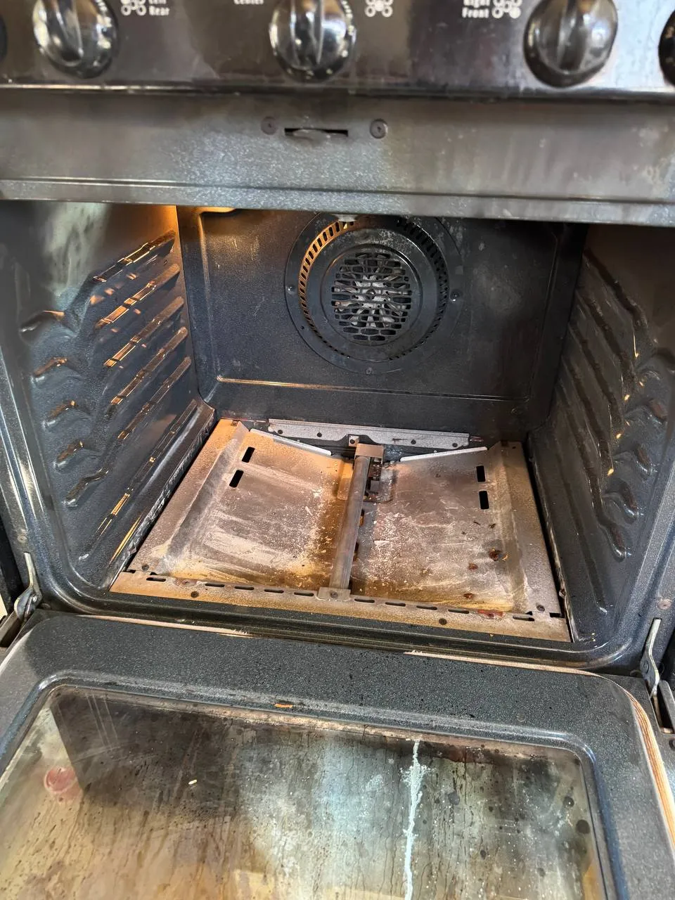 Frigidaire gas oven interior with the bottom panel lifted and the burner visible