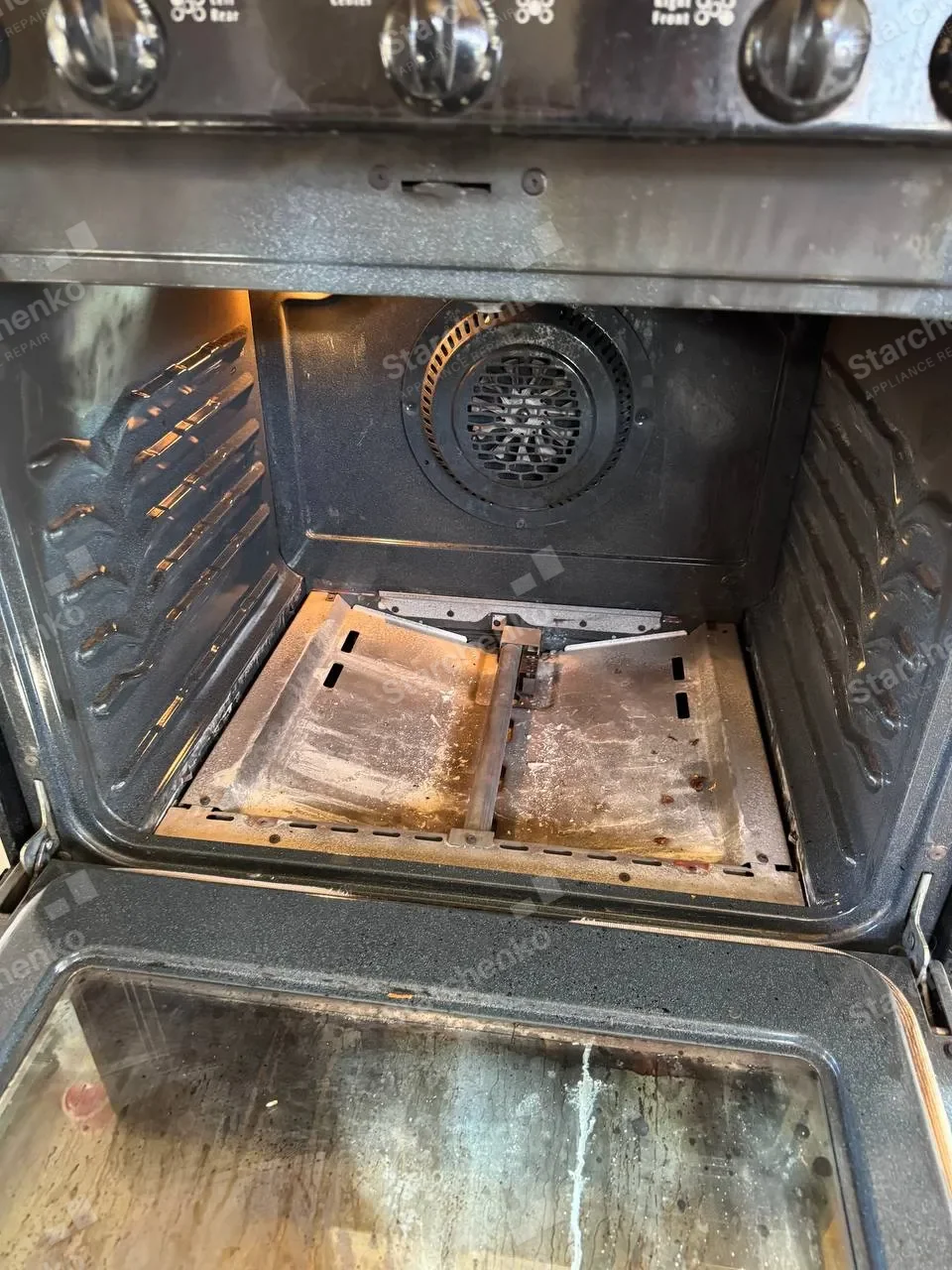 Frigidaire gas oven interior with the bottom panel lifted and the burner visible
