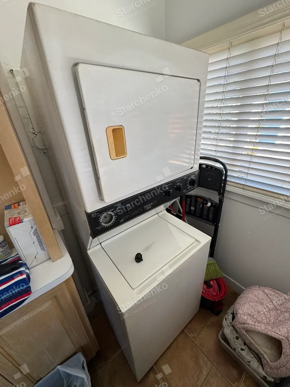 White Maytag stacked laundry center beside a window and laundry basket