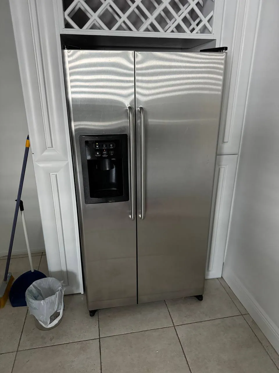 Stainless GE side-by-side refrigerator fitted into white cabinetry