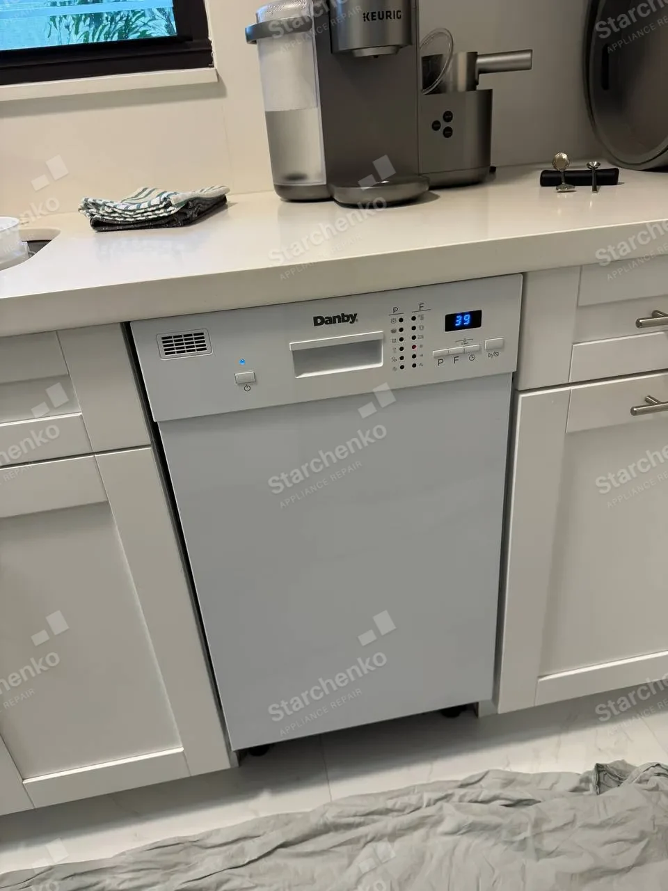 Danby built-in dishwasher in a white kitchen with its control panel lit