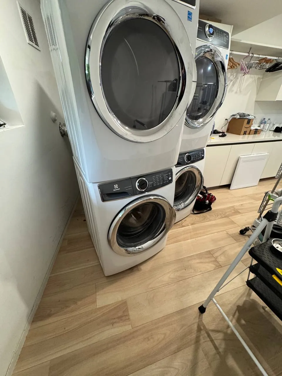 Two stacked Electrolux washer and dryer pairs in a laundry room with the dryer doors open