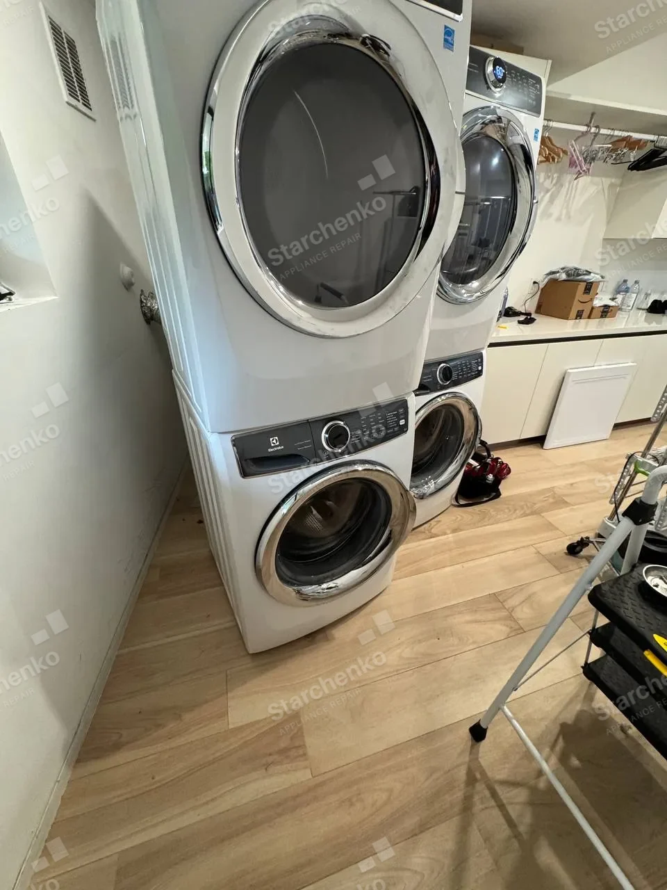 Two stacked Electrolux washer and dryer pairs in a laundry room with the dryer doors open