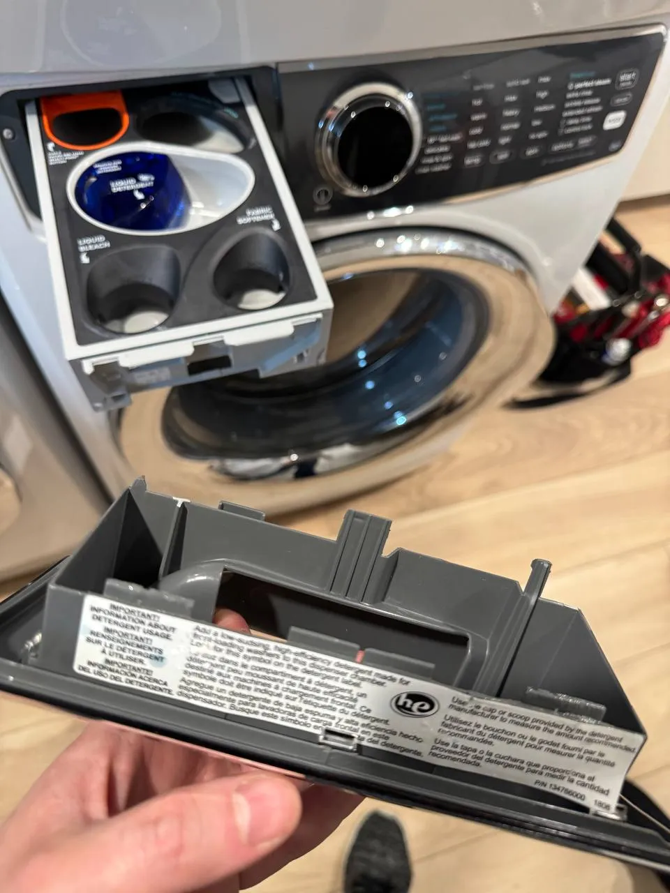 Electrolux washer detergent drawer pulled out with the dispenser insert removed and held in hand
