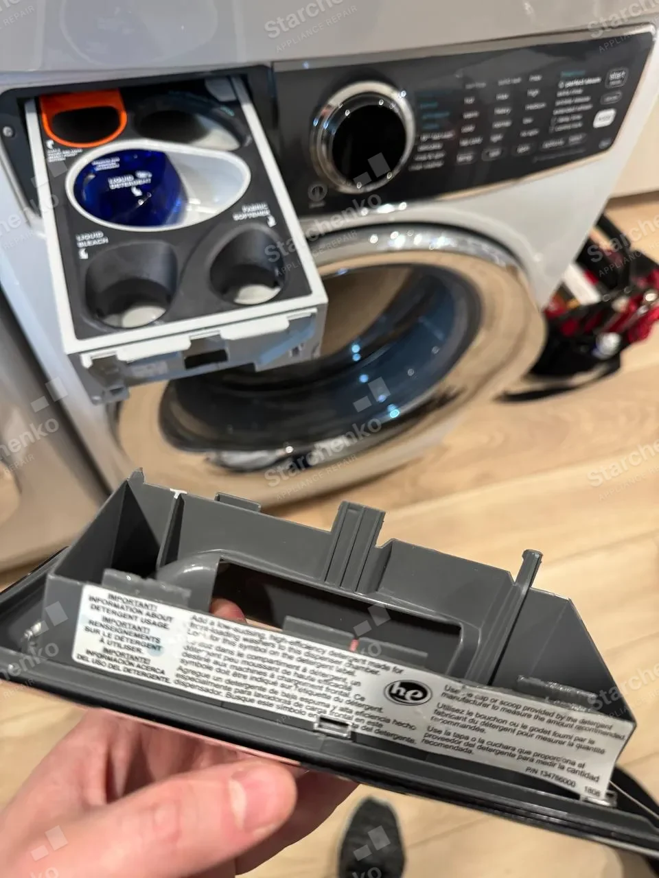 Electrolux washer detergent drawer pulled out with the dispenser insert removed and held in hand