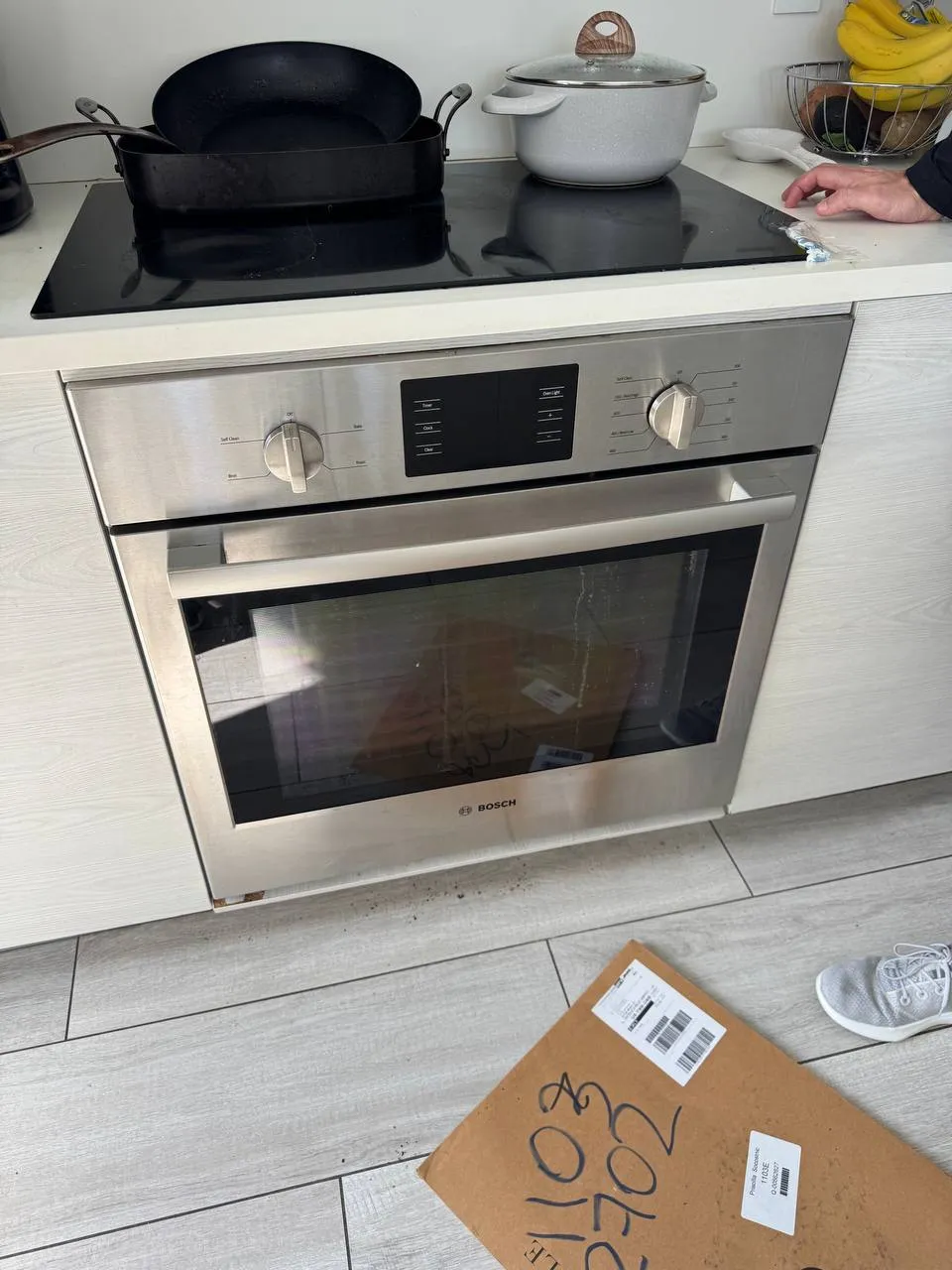 Bosch wall oven below a black glass cooktop with pots on the surface