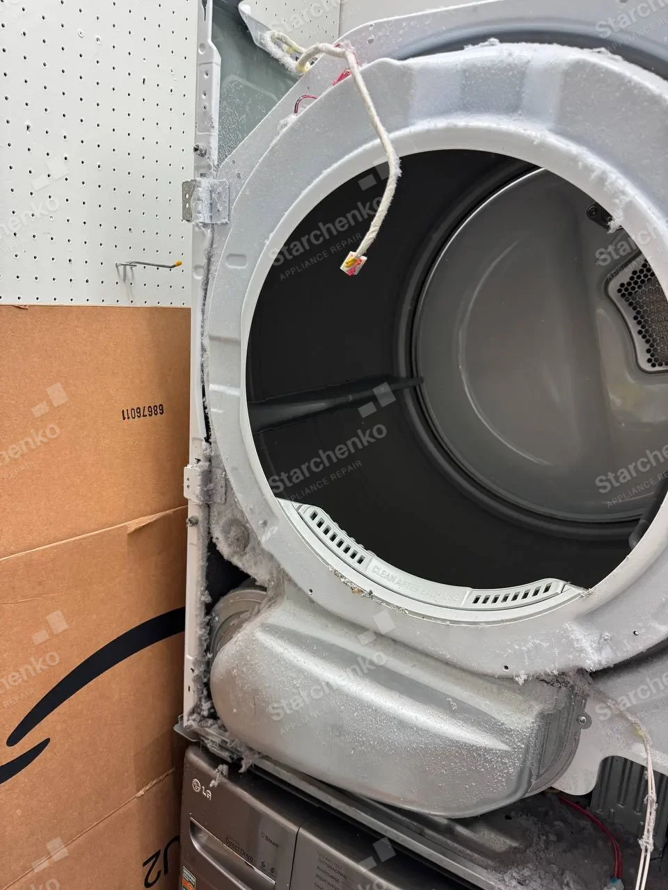 LG dryer with the front panel off, the drum and the lint-packed blower housing exposed