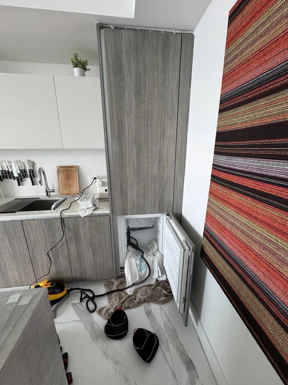Panel-ready Miele refrigerator column with the lower freezer door open and towels on the floor during a defrost