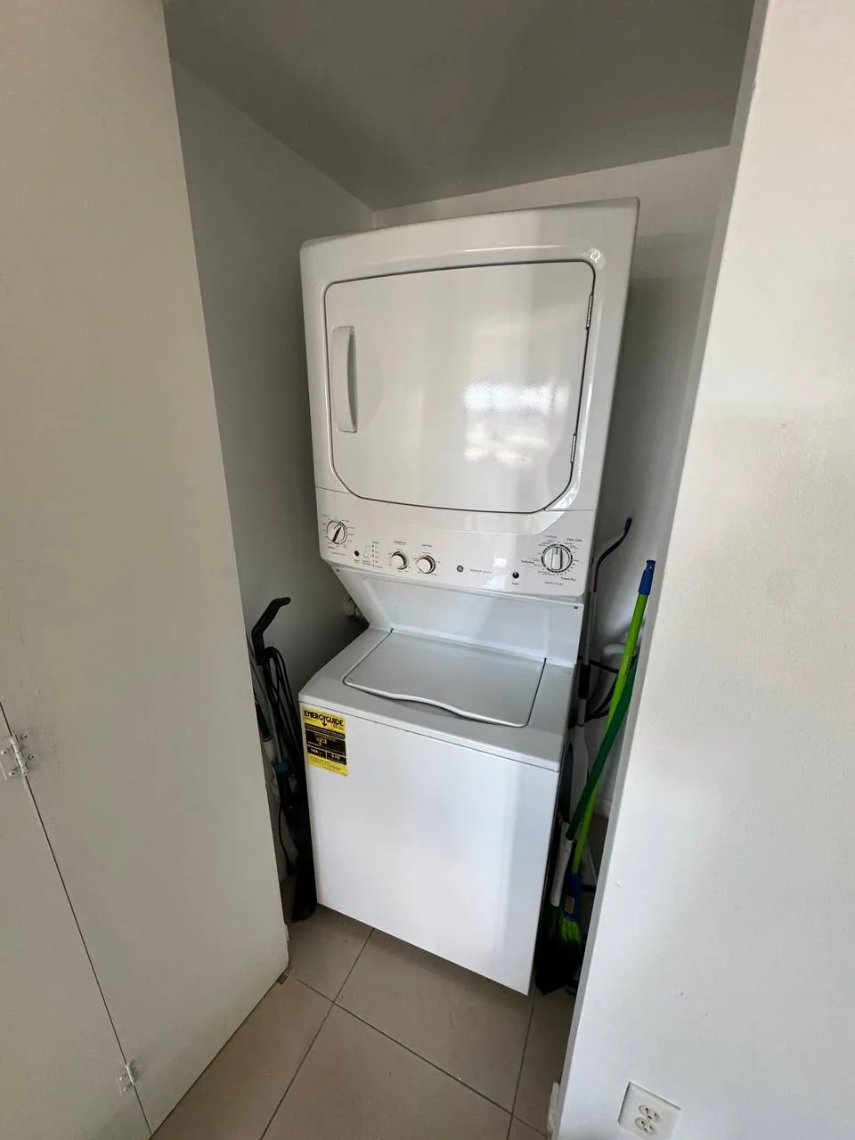 White GE stacked laundry center in a narrow utility closet