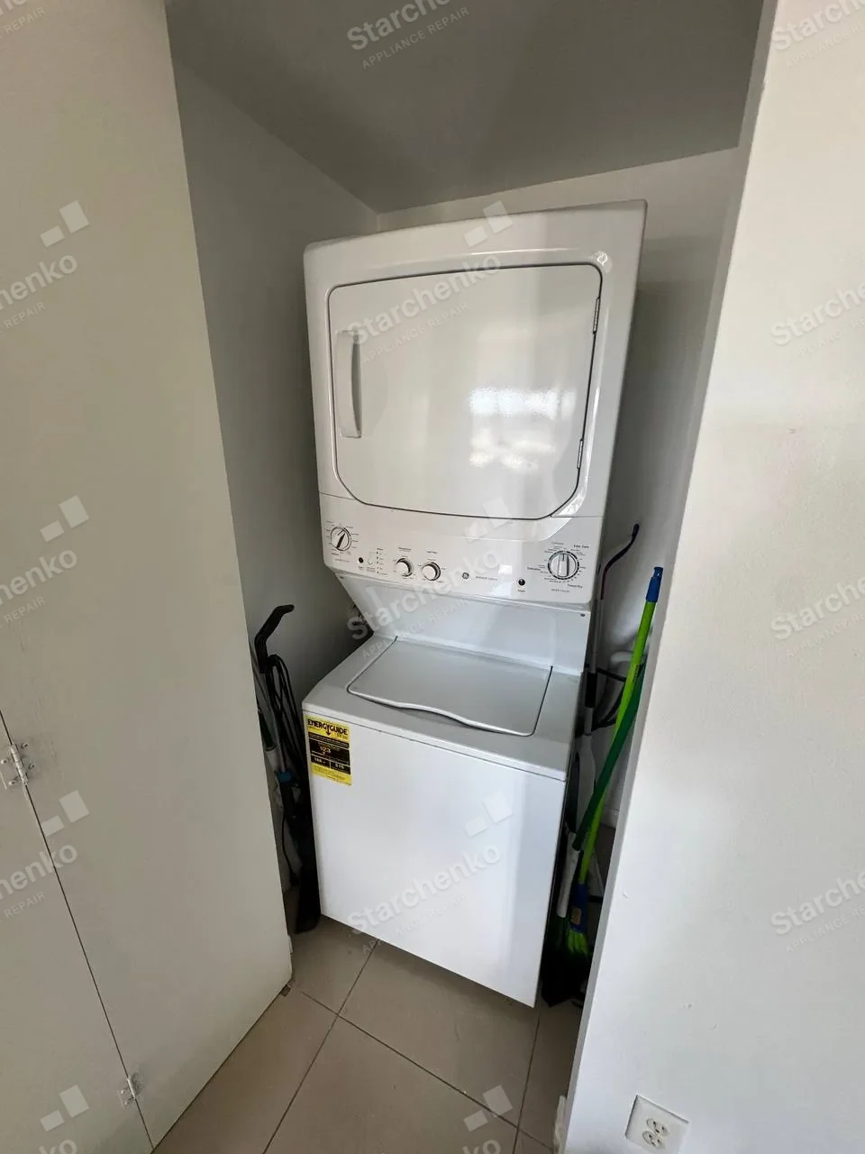White GE stacked laundry center in a narrow utility closet