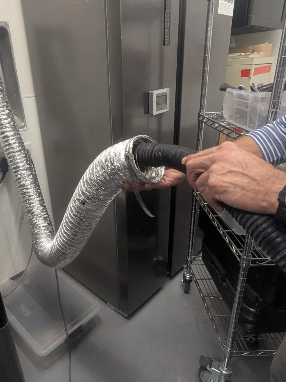 Technician joining the flexible vent duct of a commercial dryer with a clamp during a vent cleanout