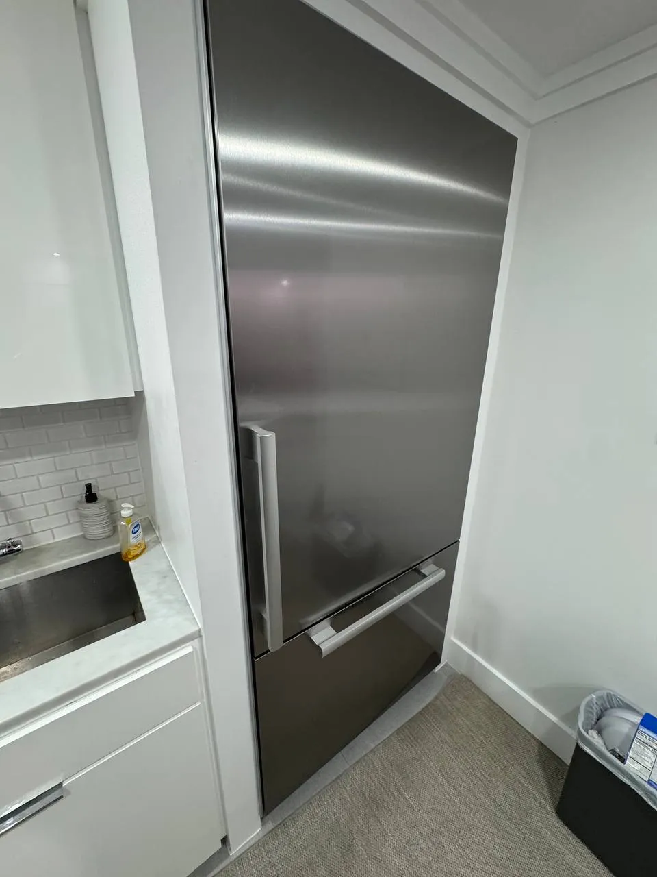 Stainless Thermador bottom-freezer refrigerator built into a white kitchenette