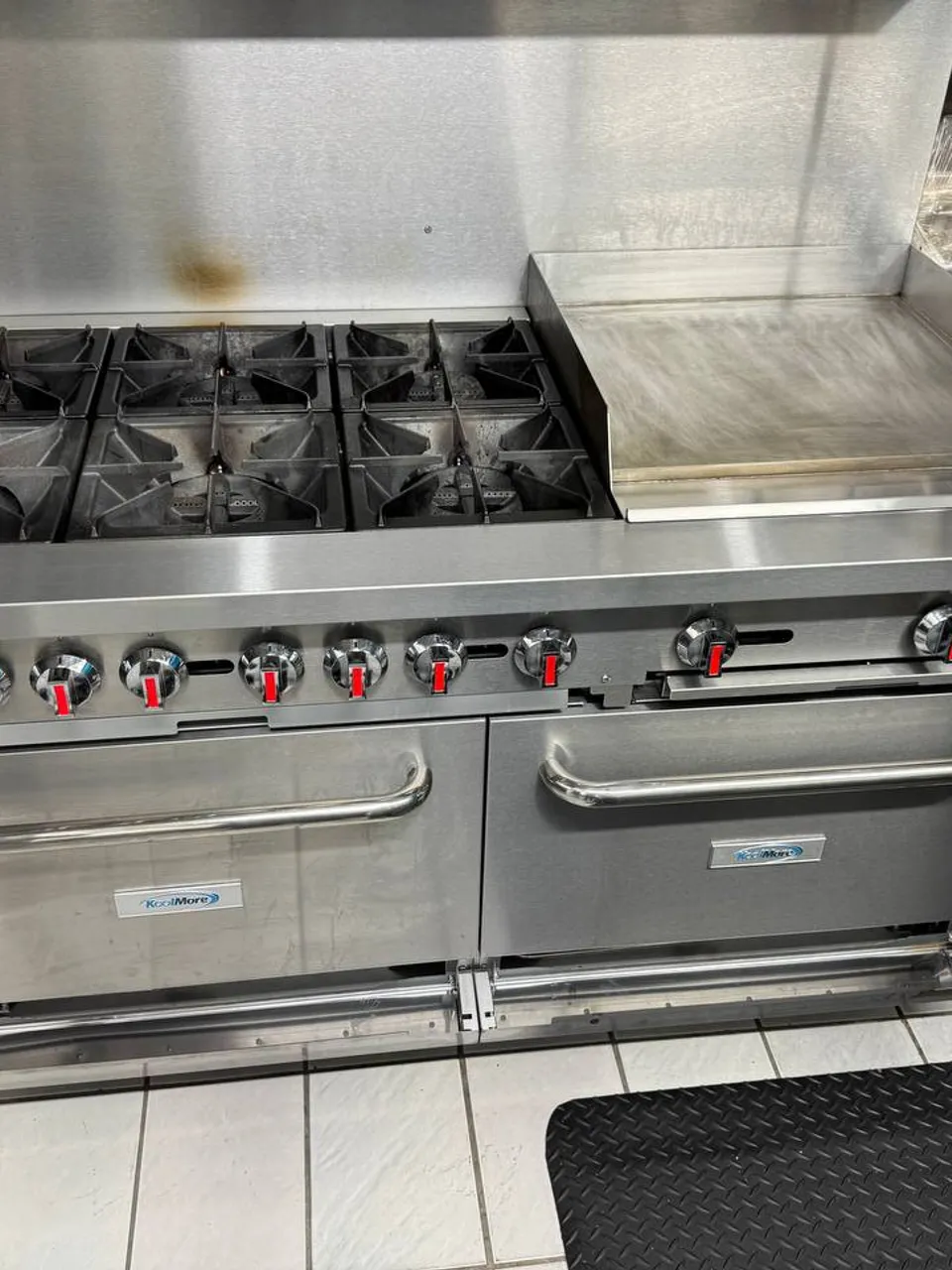 Stainless KoolMore commercial gas range with a flat-top griddle and two ovens in a restaurant kitchen