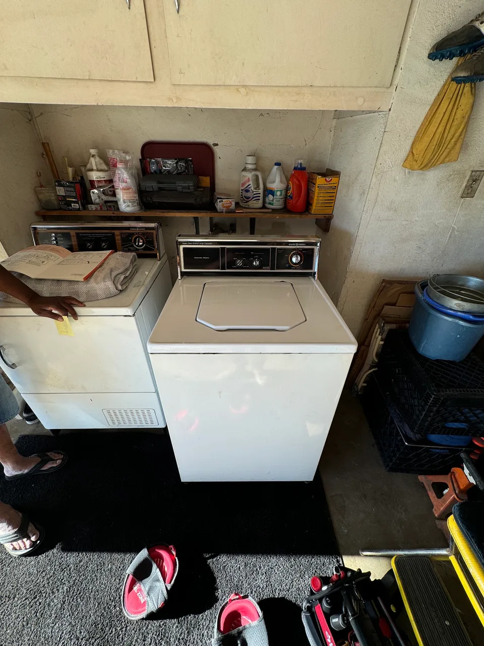 Vintage GE top-load washer next to its dryer in a garage laundry corner