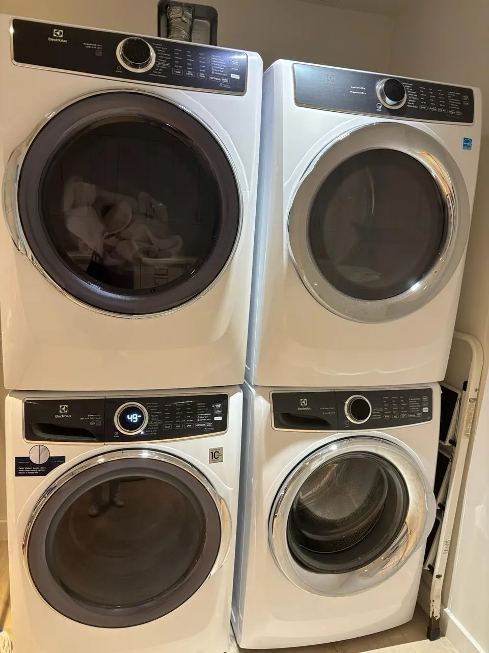 Two stacked Electrolux washer and dryer pairs side by side in a laundry room