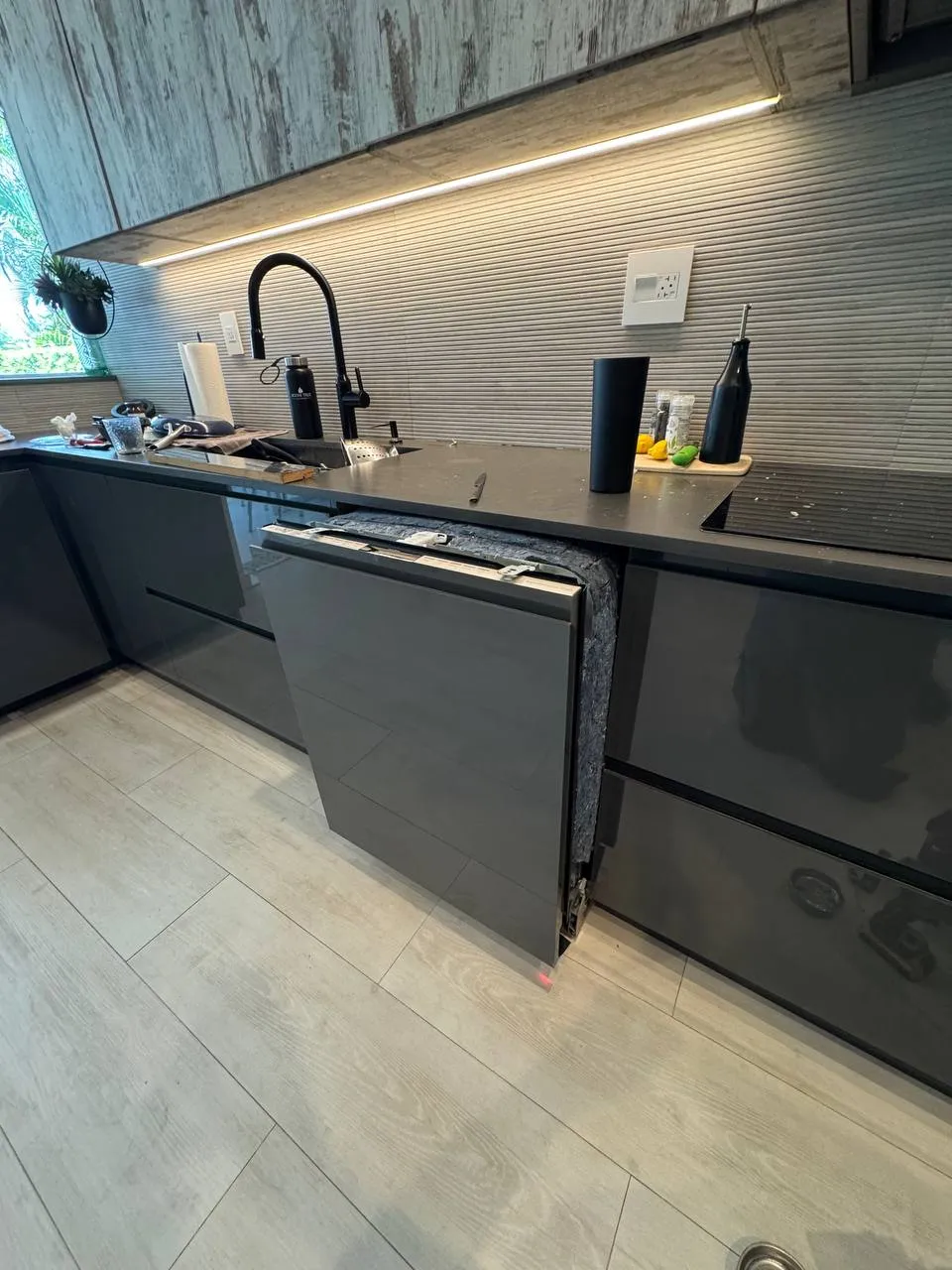 Panel-ready LG dishwasher pulled forward from dark kitchen cabinets