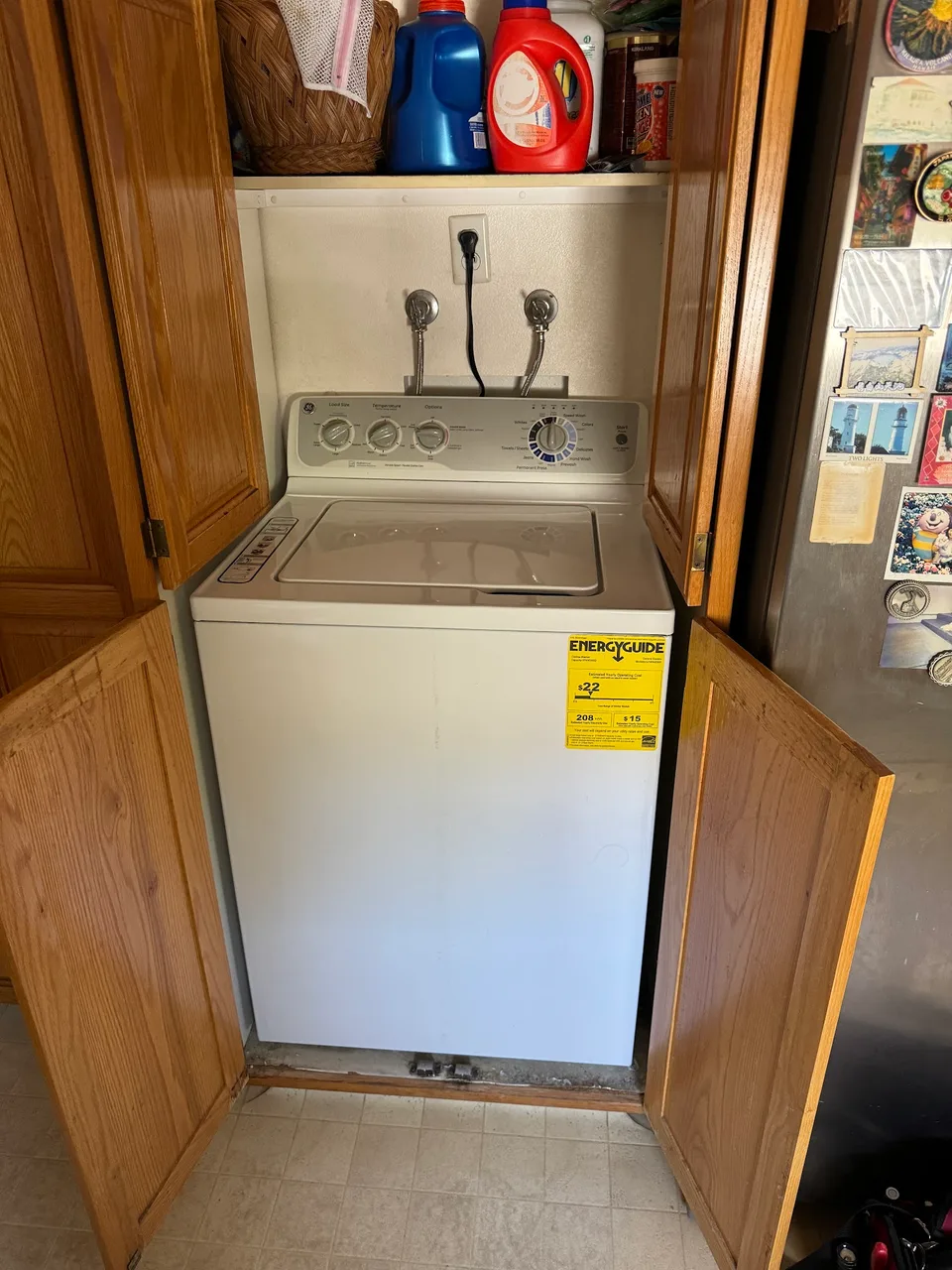 White top-load washer inside a wooden cabinet nook with the doors open