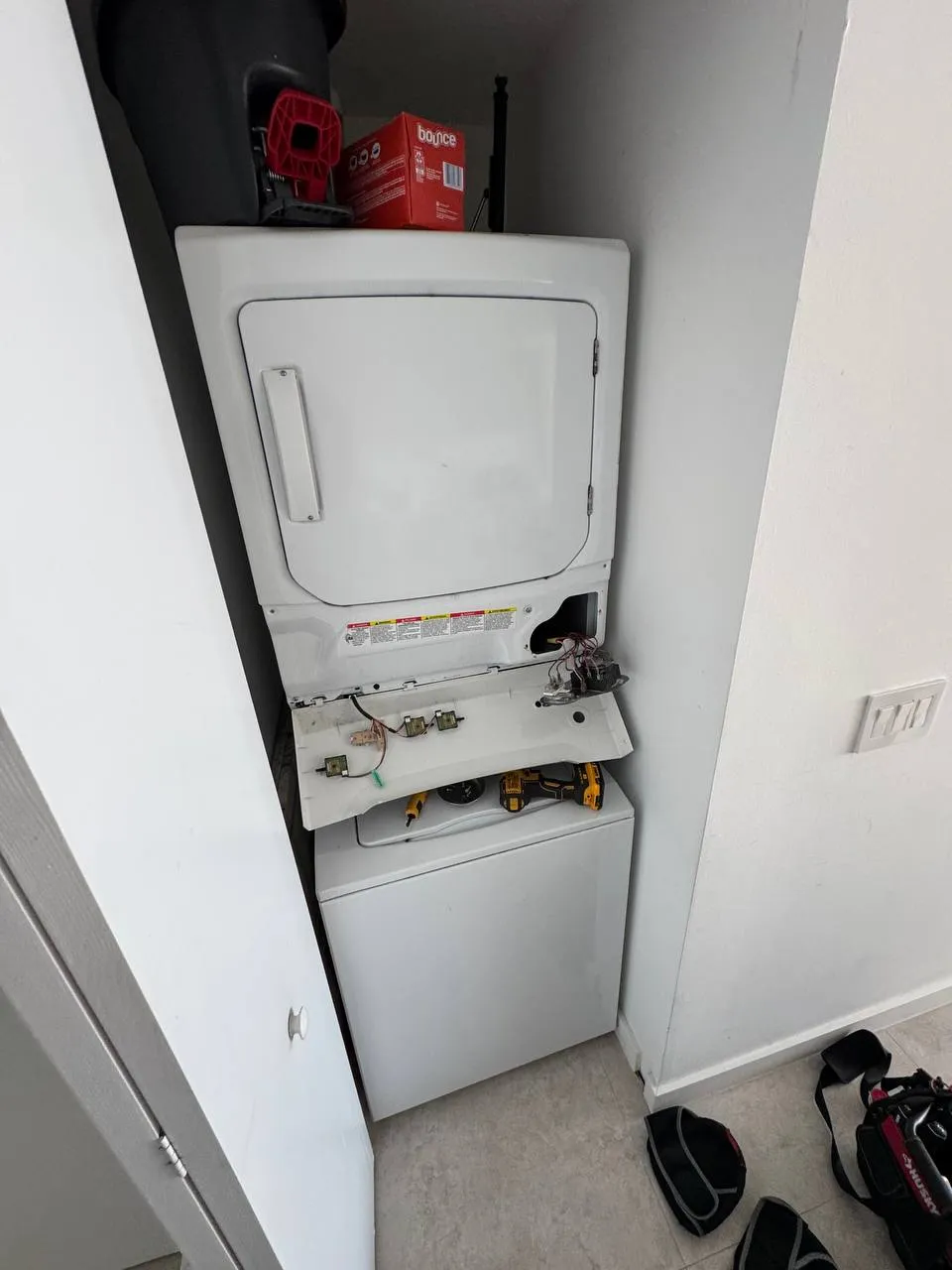Frigidaire stacked laundry center with the control panel lowered and wiring visible