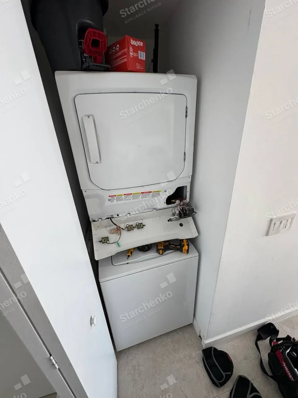 Frigidaire stacked laundry center with the control panel lowered and wiring visible